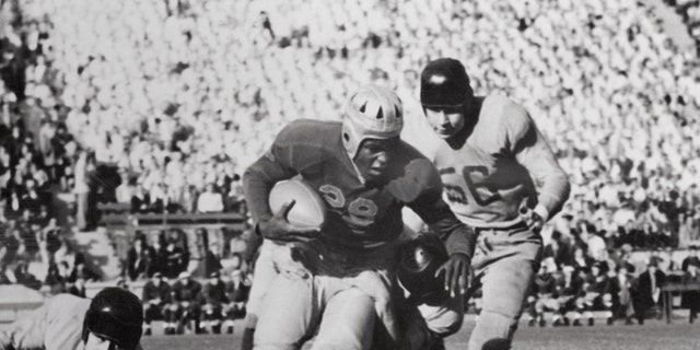 An 82-yard drive in the final five minutes of the game led the UCLA football team to a 13-13 tie with Oregon State College in an open battle in front of 40,000 fans.  The statistics showed that the two teams were playing almost evenly with UCLA having a slight edge.  Photo shows UCLA right half Jackie Robinson (#28) being tackled after receiving an 8-yard pass from teammate Kenny Washington.  Oregon State right tackle Walter Jelsma is shown at #56.