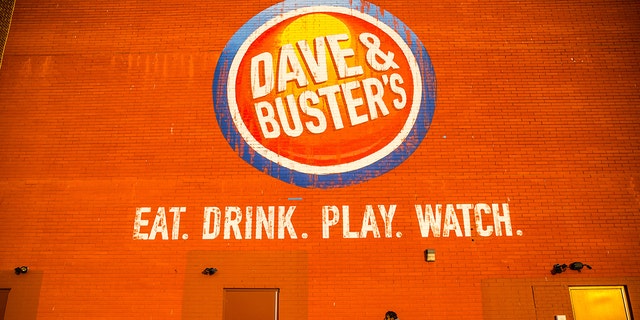 Pedestrians walk past signage for a Dave &amp; Buster's Entertainment Inc. location in Pelham, New York, U.S. on Friday, March 24, 2017. 