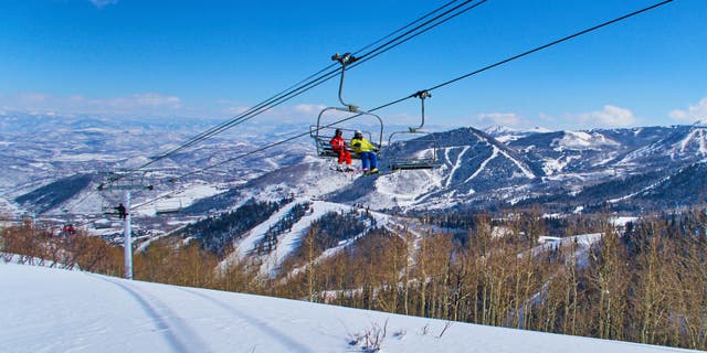 Skiers sit in a chairlift with a panoramic view of the Wasatch Range in the Rocky Mountains on March 2, 2015 in Park City, Utah, USA.