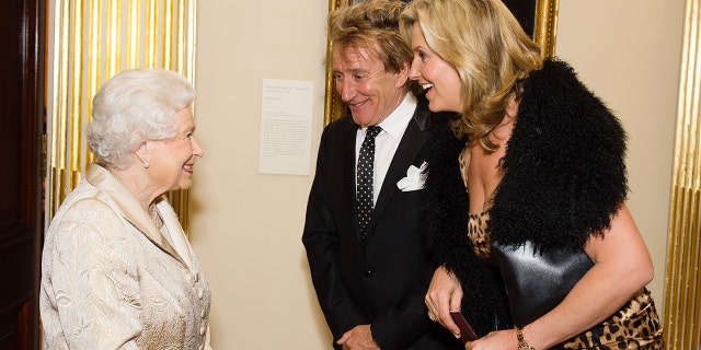 Queen Elizabeth II greets Sir Rod Stewart and wife, Penny Lancaster, after he was awarded a knighthood in recognition of his services to music and charity earlier in the day as they attend a reception and awards ceremony at the Royal Academy of Arts on October 11, 2016, in London, England. 