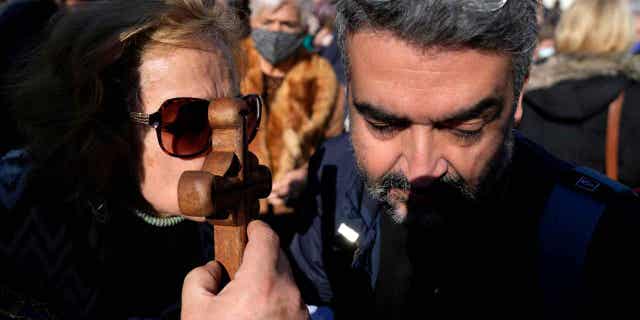 A woman kisses the cross during an Epiphany ceremony at a suburb in Piraeus port, near Athens, Greece, on Jan. 6, 2023.