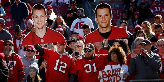 Tampa Bay Buccaneers fans hold up cardboard cutouts of Rob Gronkowski, left, and Tom Brady during the game against the Los Angeles Rams in the NFC divisional playoffs at Raymond James Stadium, Jan. 23, 2022, in Tampa, Florida.