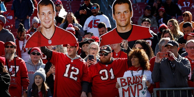 Tampa Bay Buccaneers fans hold up cardboard cutouts of Rob Gronkowski, left, and Tom Brady during the game against the Los Angeles Rams in the NFC divisional playoffs at Raymond James Stadium, Jan. 23, 2022, in Tampa, Florida.