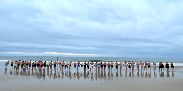Sunday Swimmers hold hands as they walk together into the ocean at Robert Moses State Park on Jan. 22, 2023.