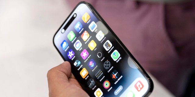 Un colega de Apple sostiene uno de los nuevos iPhone Pro durante un evento de lanzamiento de un nuevo producto en Apple Park el 7 de septiembre de 2022 en Cupertino, California.  y nuevos AirPods Pros en el evento. 