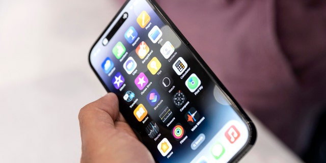 An Apple associate holds one of the new iPhone Pros during a launch event for new products at Apple Park in Cupertino, California, on September 7, 2022.