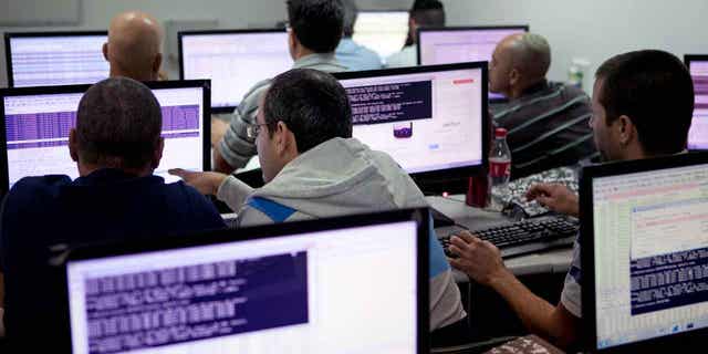 Israelis are pictured above working on computers at the "CyberGym" school in the coastal city of Hadera. Investments in Israel's tech sector dropped by nearly half in 2022, reflecting a global economic slowdown. 