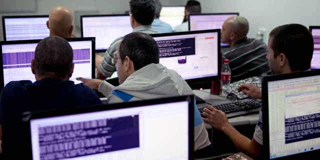 Israelis are pictured above working on computers at the "CyberGym" school in the coastal city of Hadera. Investments in Israel's tech sector dropped by nearly half in 2022, reflecting a global economic slowdown.