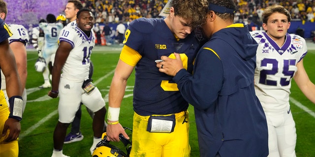 El mariscal de campo de Michigan, JJ McCarthy, abraza a un entrenador después del Fiesta Bowl, el sábado 31 de diciembre de 2022, en Glendale, Arizona.