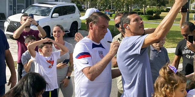 File: Former Brazilian President Jair Bolsonaro (middle) meets with supporters outside the villa where he's staying near Orlando, Florida, Wednesday, January 4, 2023.