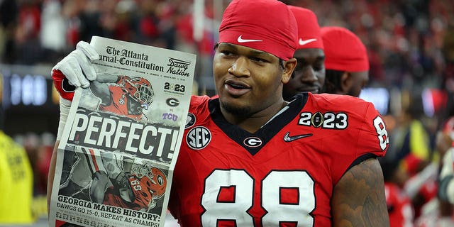 Jalen Carter, #88 of the Georgia Bulldogs, celebrates with a newspaper reading, "Perfect!" after defeating the TCU Horned Frogs in the College Football Playoff National Championship game at SoFi Stadium on January 9, 2023, in Inglewood, California. Georgia defeated TCU 65-7.