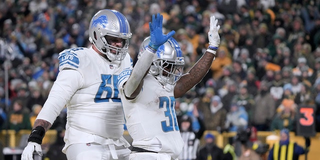 Detroit Lions running back Jamaal Williams, #30, celebrates after scoring as teammate Taylor Decker, #68, looks on during the second half of an NFL football game Sunday, January 8, 2023 in Green Bay, Wisconsin.