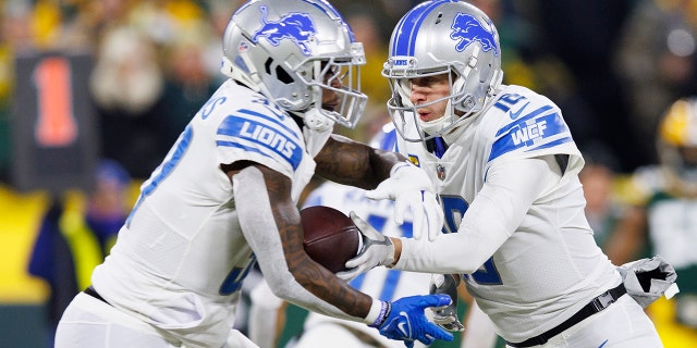 Jan 8, 2023; Green Bay, Wisconsin, USA;  Detroit Lions quarterback Jared Goff (16) hands the football off to running back Jamaal Williams (30) during the first quarter against the Green Bay Packers at Lambeau Field.