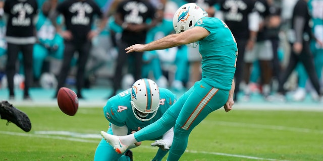 Le botteur des Dolphins de Miami, Jason Sanders, lance un panier alors que le parieur Thomas Morstead tient pendant la première moitié d'un match de football de la NFL contre les Jets de New York, le dimanche 8 janvier 2023, à Miami Gardens, en Florida.
