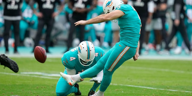 Le botteur des Dolphins de Miami, Jason Sanders, lance un panier alors que le parieur Thomas Morstead tient pendant la première moitié d'un match de football de la NFL contre les Jets de New York, le dimanche 8 janvier 2023, à Miami Gardens, en Florida.