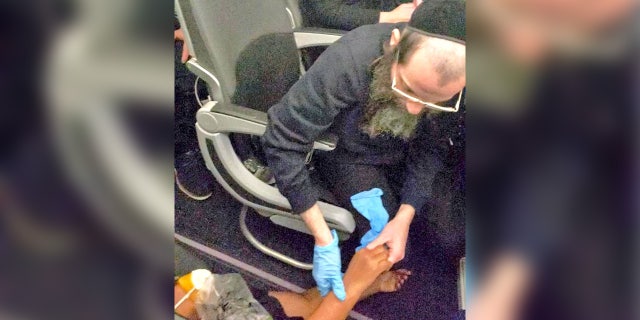 A man is seen helping a woman after she passed out during a JetBlue flight from New York to Florida on Thursday, January 26, 2023.