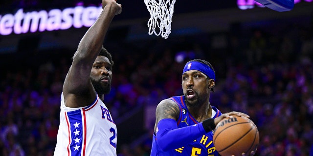 Denver Nuggets' Kentavious Caldwell-Pope passes the ball as Philadelphia 76ers' Joel Embiid defends, Saturday, Jan. 28, 2023, in Philadelphia.