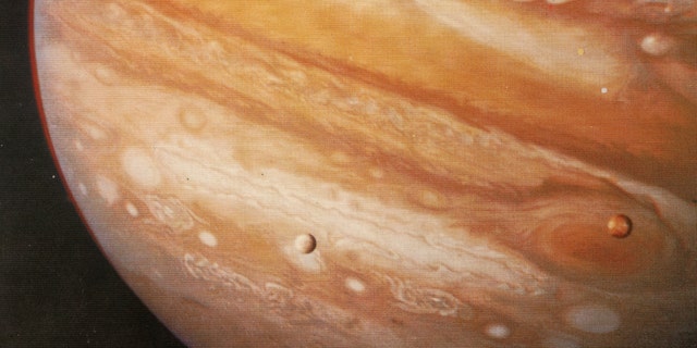 The planet Jupiter, 1979. Taken from Voyager 1 at 20 million kilometres this pictures shows the Great Red Spot, a storm that has been raging for hundreds of years, and two of Jupiter's moons - Io over the Red Spot and Europa. 