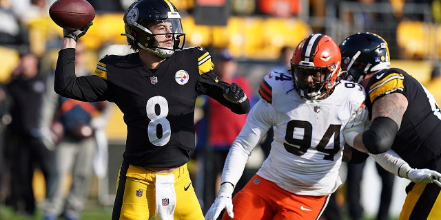 El mariscal de campo de los Pittsburgh Steelers, Kenny Pickett (8), busca pasar bajo la presión del ala defensiva de los Cleveland Browns, Alex Wright (94), durante la primera mitad de un partido de fútbol americano de la NFL en Pittsburgh, el domingo 8 de enero de 2023. 