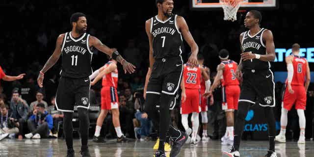 Kevin Durant (7) caminando por el campo entre sus compañeros Kyrie Irving, a la izquierda, y Edmond Sumner, a la derecha, durante un partido contra los Washington Wizards.