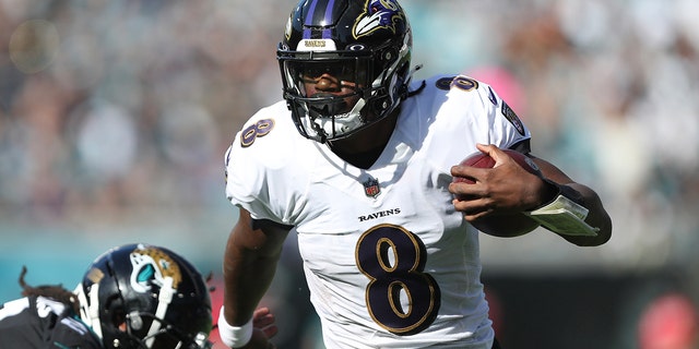 Lamar Jackson of the Baltimore Ravens carries the ball past Rayshawn Jenkins of the Jacksonville Jaguars during the first half at TIAA Bank Field Nov. 27, 2022, in Jacksonville, Fla.