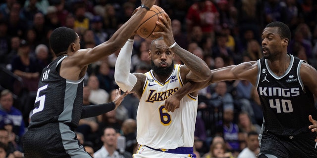 Kings guard De'Aaron Fox, left, and forward Harrison Barnes defend against Los Angeles Lakers forward LeBron James in Sacramento, Saturday, Jan. 7, 2023.