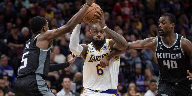 El escolta de los Kings, De'Aaron Fox, a la izquierda, y el alero Harrison Barnes defienden contra el alero de los Lakers de Los Ángeles, LeBron James, en Sacramento, el sábado 7 de enero de 2023.