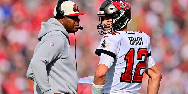 Tom Brady (12), de los Tampa Bay Buccaneers, habla con el coordinador ofensivo Byron Leftwich durante el segundo cuarto contra los Carolina Panthers en el Raymond James Stadium el 1 de enero de 2023 en Tampa, Florida.