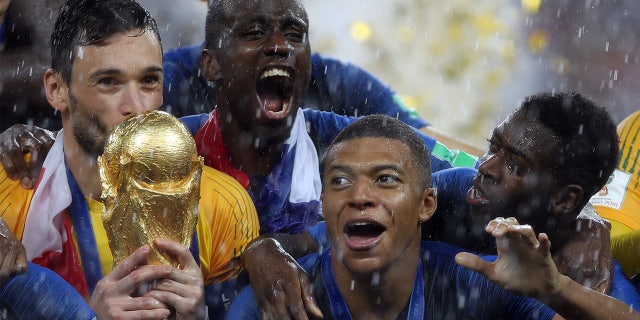 Hugo Lloris surrounded by his France teammates and holding the World Cup trophy after besting Croatia at the Luzhniki Stadium in Moscow on July 15, 2018.