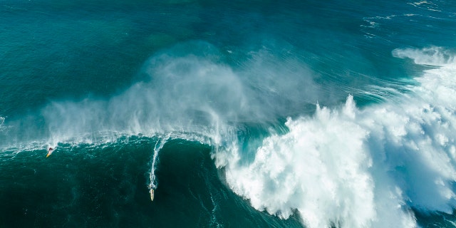 An aerial view of local lifeguard Luke Shepperson riding a giant wave on his way to victory during the Eddie Ekau Big Wave Invitational on January 22, 2023 in Waimea Bay, Haleiwa, Hawaii.