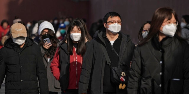 People wearing masks walk a street in Beijing on Friday, January 6, 2023. 