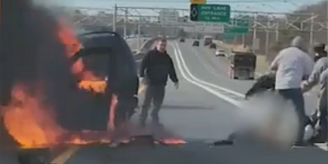 Good Samaritans are seen saving a woman from a fiery crash in New York on Monday.