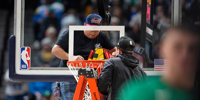 Workers struggle to replace the rim during a game between the Celtics and the Nuggets in Denver, Sunday, Jan. 1, 2023.