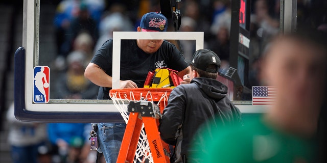 Workers struggle to replace the rim during a game between the Celtics and the Nuggets in Denver, Sunday, Jan. 1, 2023.