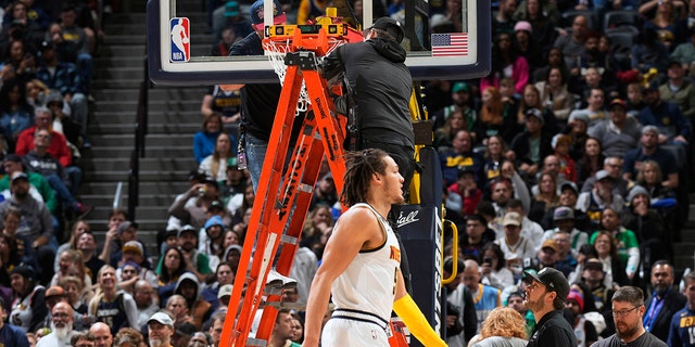 Denver Nuggets forward Aaron Gordon warms up while workers change out the rim after it was bent by Boston Celtics center Robert Williams III, Sunday, Jan. 1, 2023, in Denver.