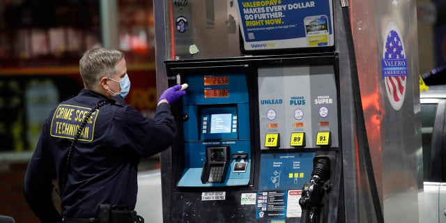 An Oakland police crime scene technician investigates the Valero gas station where the shooting happened in Oakland, California on Monday, Jan. 23.