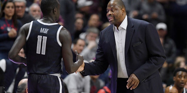 El entrenador en jefe de Georgetown, Patrick Ewing, a la derecha, habla con el número 11 de Georgetown, Akok Akok, en la segunda mitad de un partido de baloncesto universitario de la NCAA contra Connecticut el martes 20 de diciembre de 2022 en Storrs, Connecticut.