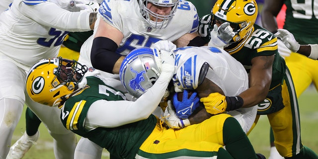 Quay Walker #7 of the Green Bay Packers tackles Jamaal Williams #30 of the Detroit Lions during the first quarter at Lambeau Field on January 8, 2023 in Green Bay, Wisconsin. 