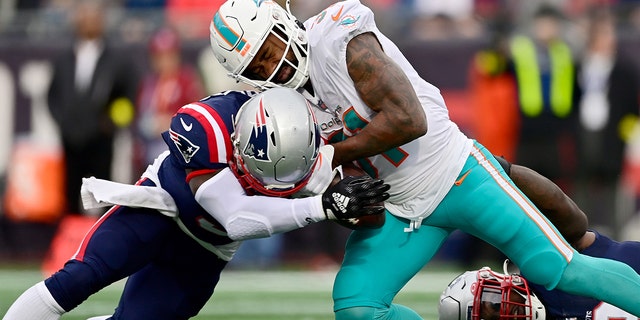 Raheem Mostert of the Miami Dolphins is tackled by Matthew Judon of the New England Patriots at Gillette Stadium on Jan. 1, 2023, in Foxborough, Massachusetts.