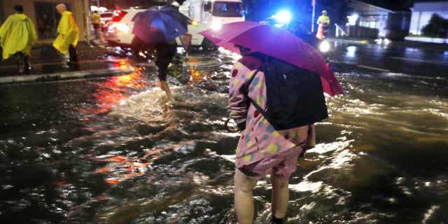 People cross a flooded street in Auckland, on Jan. 27, 2023. Record levels of rainfall pounded New Zealand's largest city over the weekend. The country's northern region expects more flooding in the coming days.
