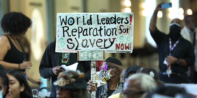 Los Angeles long-time resident, Walter Foster, age 80, holds up a sign as the Reparations Task Force meets to hear public input on reparations at the California Science Center in Los Angeles on Sept. 22, 2022.