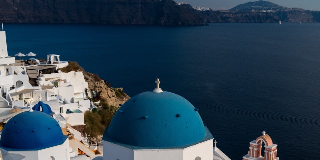 A view of the town of Oia with its whitewashed houses and blue-domed churches in Santorini on the Aegean Sea.