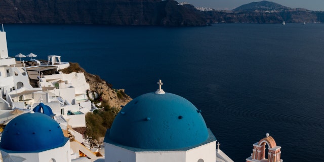 Pohled na Oiu s jejími vápnem umytými domy a kostely s modrou kupolí na ostrově Santorini v Egejském moři.