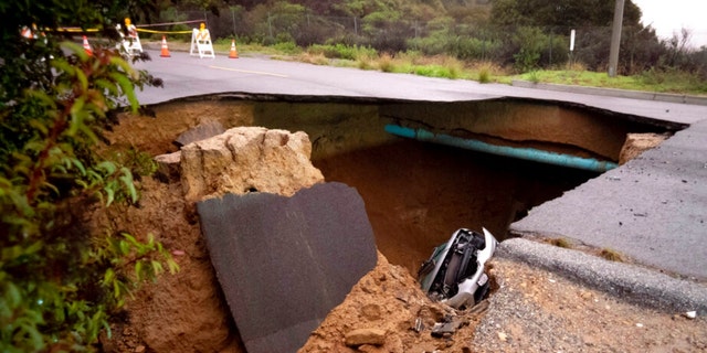 Cars remain in a large sinkhole along Iverson Road in Chatsworth, Calif., on Jan. 10, 2023. 