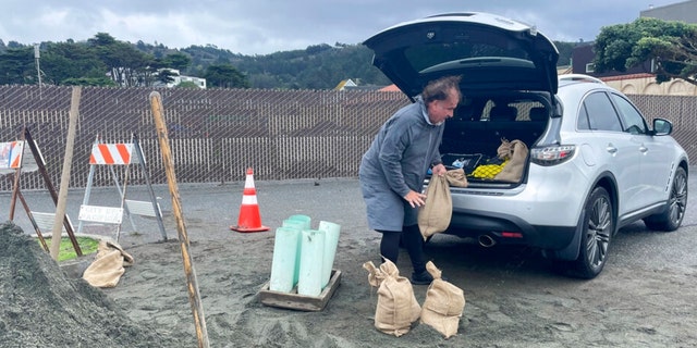 A man loads the back of his car with sandbags, Wednesday, Jan. 4, 2023, in Pacifica, Calif. 
