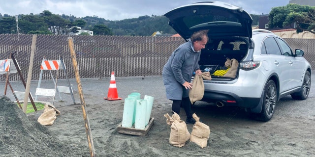 A man loads the back of his car with sandbags, Wednesday, Jan. 4, 2023, in Pacifica, Calif. 