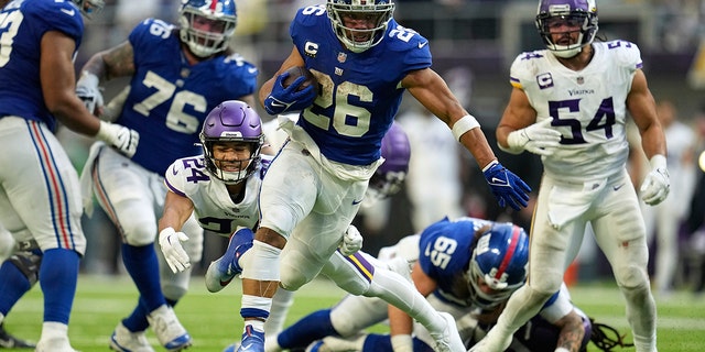 New York Giants' Saquon Barkley runs from Vikings safety Camryn Bynum during a 27-yard touchdown run, Dec. 24, 2022, in Minneapolis.