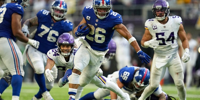 New York Giants running back Saquon Barkley (26) runs from Minnesota Vikings safety Camryn Bynum (24) during a 27-yard touchdown run in the second half of a game on December 24, 2022 in Minneapolis.