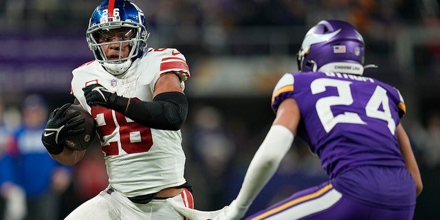 New York Giants' Saquon Barkley looks to get past Minnesota Vikings' Camryn Bynum during the playoff game Sunday, Jan. 15, 2023, in Minneapolis.