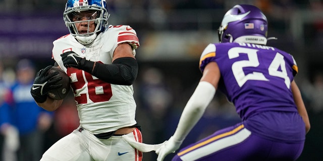 Saquon Barkley de los New York Giants busca superar a Camryn Bynum de los Minnesota Vikings en el partido de playoffs el domingo 15 de enero de 2023 en Minneapolis.